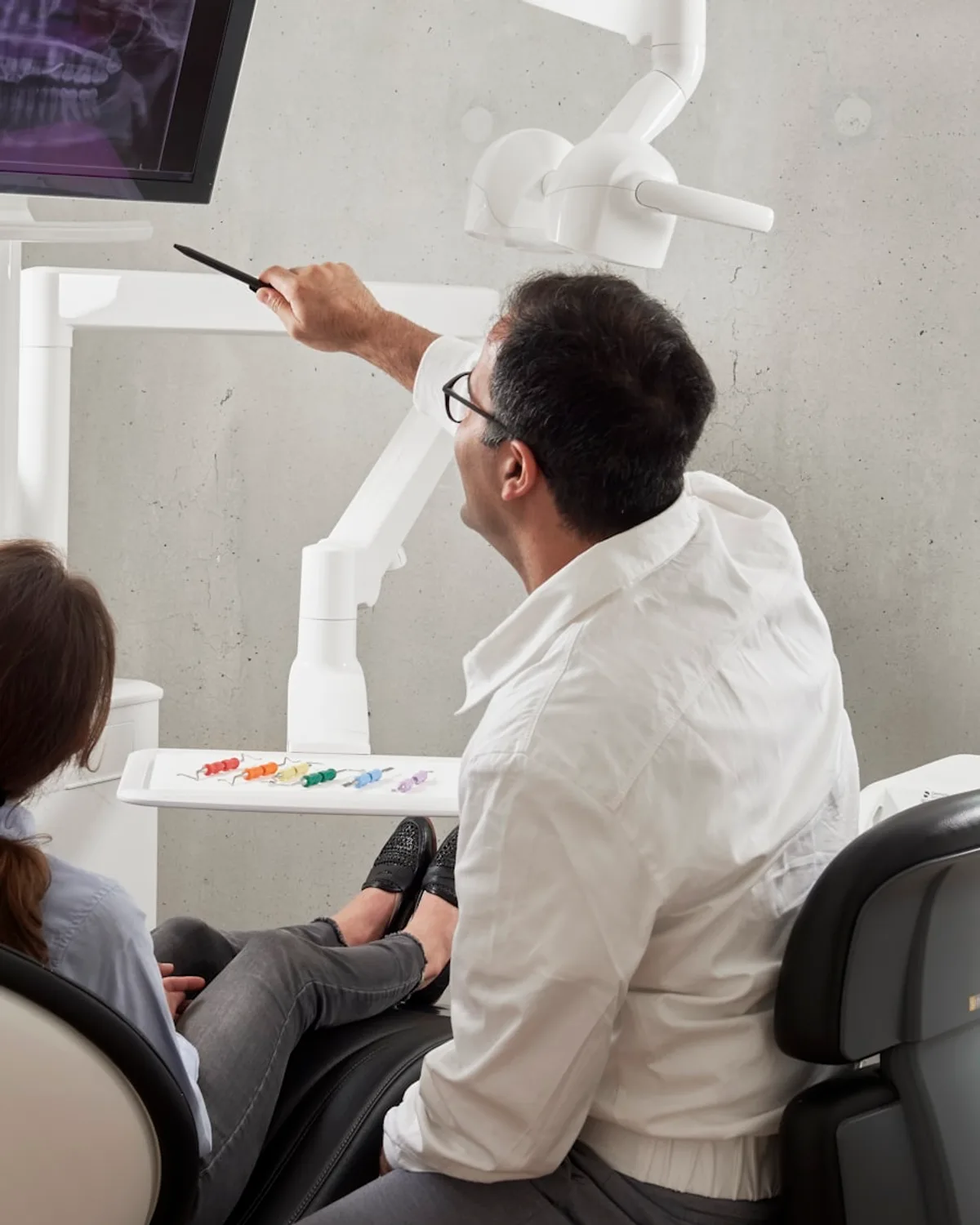 A dentist showing a patient their X-ray on a chairside screen