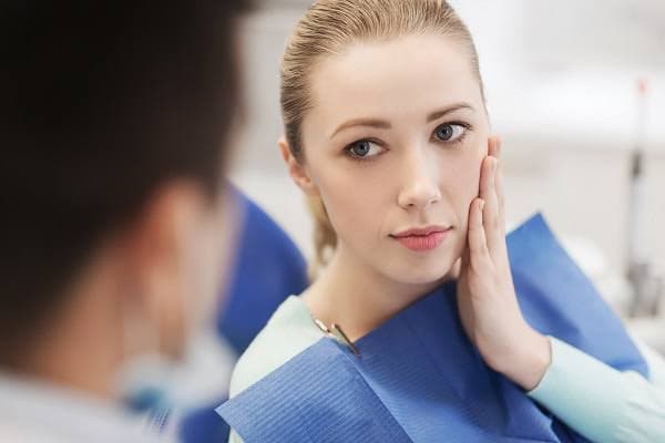 Woman holding her cheek with tooth pain before seeking emergency dental care in Seoul.